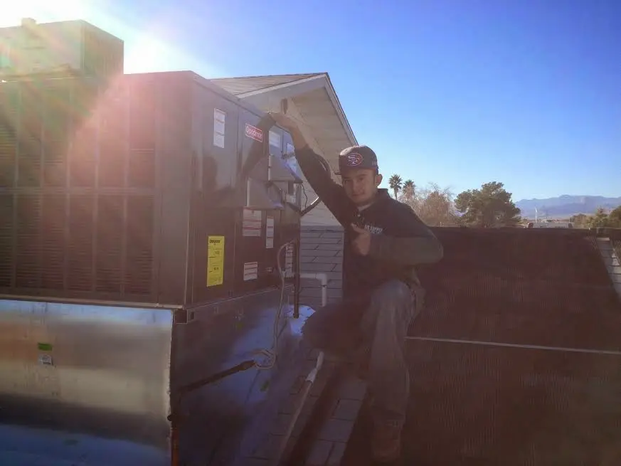 HVAC technician performing Air Duct Cleaning on a rooftop unit in Marilla